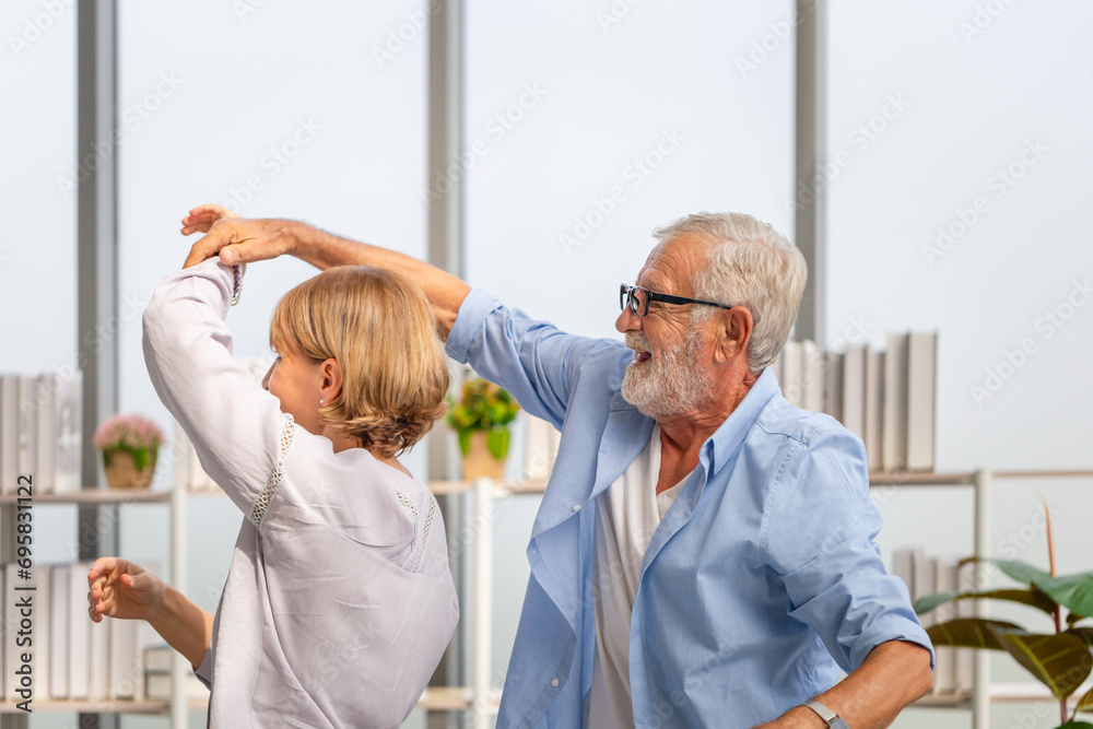 Obraz premium Senior couple wife and husband dancing to music together in living room, retired man and woman having fun free time together at home