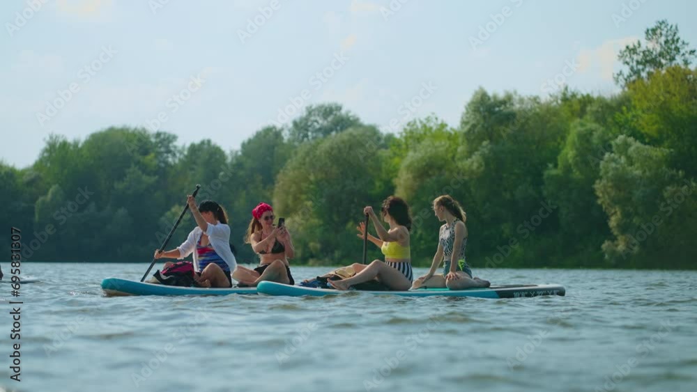 Happy Female Friends Floating On Paddleboard In River And Taking Pictures By Smartphone