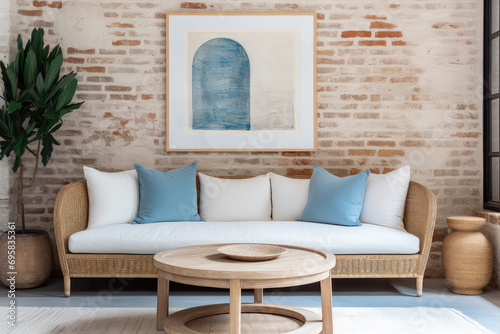 The charm of French country farmhouse interior design, modern living room featuring a wicker round coffee table, a cozy white sofa with blue pillows, and a beige brick wall adorned with a poster frame