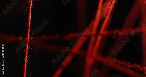 Stretched red threads in different directions and planes on a black background. Solving a crime