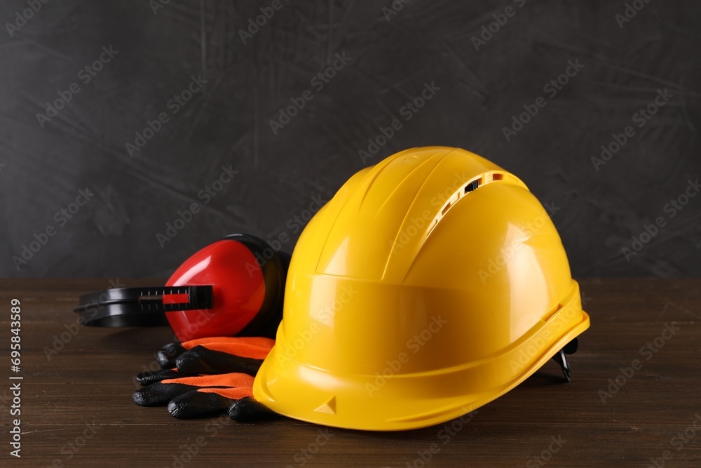Hard hat, earmuffs and gloves on wooden table. Safety equipment Hard hat, earmuffs and gloves on wooden table. Safety equipment