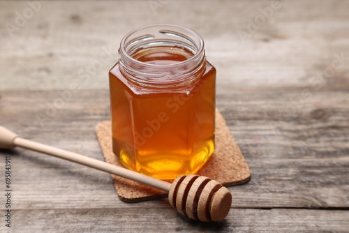 Sweet honey in jar and dipper on wooden table