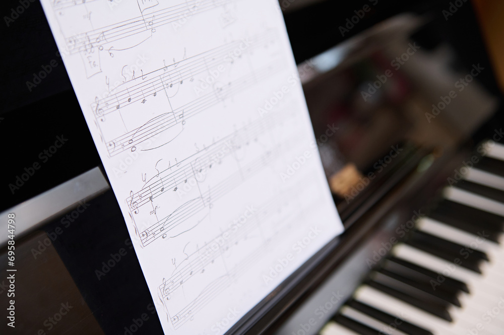 Obraz premium Still life shot. Cropped View of old vintage classical wooden piano and music notes on white paper sheet