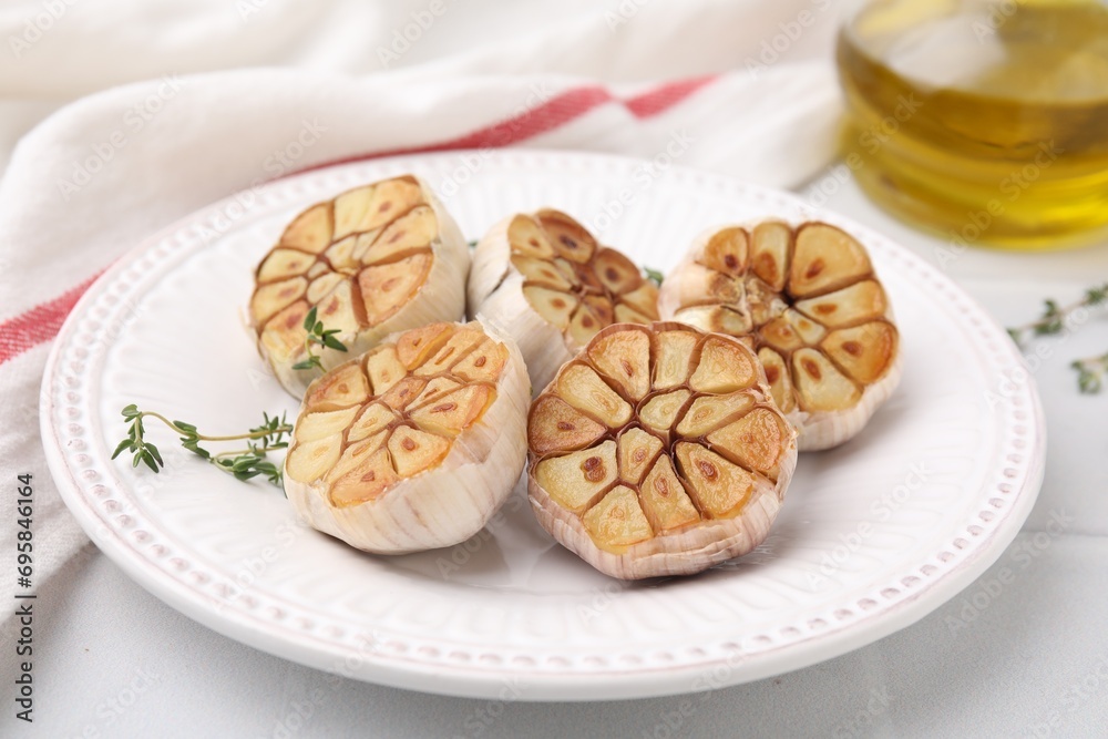 Heads of fried garlic and thyme on white table, closeup Heads of fried garlic and thyme on white table, closeup