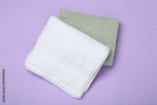 Different soft towels on violet background, top view