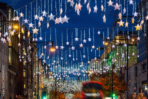 Festive Christmas decorations in the streets of London with red bus traffic during night time