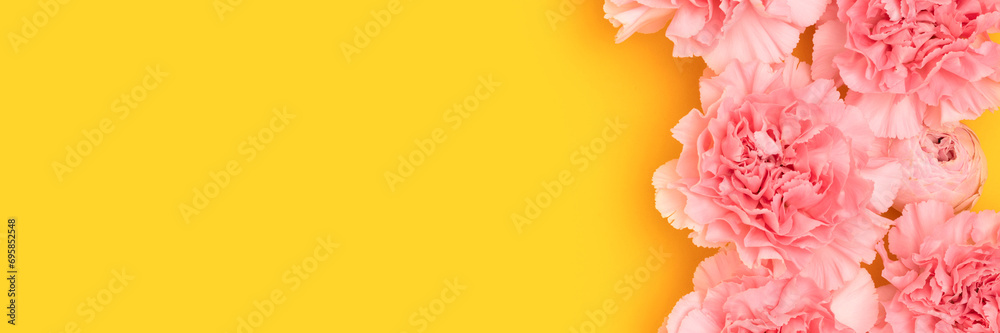 Banner with pink carnation and rose flowers on a yellow background. Selective focus.