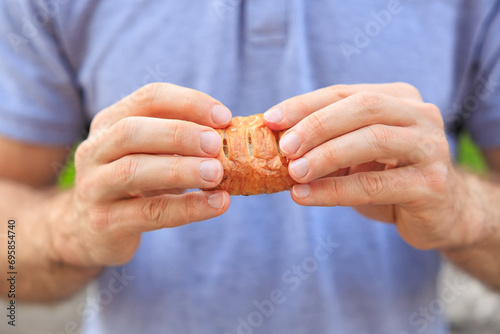 A man's hand holds a mini puff pastry with cheese, snack and fast food concept. Selective focus on hands