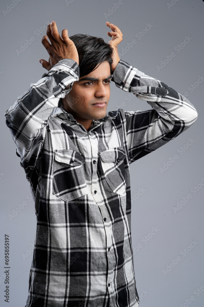 Studio shot of young Indian man wearing checkered shirt against gray background Studio shot of young Indian man wearing checkered shirt against gray background