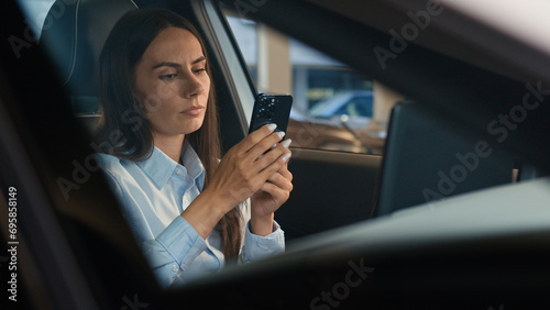 Caucasian woman girl lady driver businesswoman sitting inside car automobile at parking lot browsing smartphone stress worried mobile phone bad news thinking sad unhappy upset anxiety failure problem © Yuliia