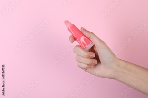 Woman with lip balm on pink background, closeup photo