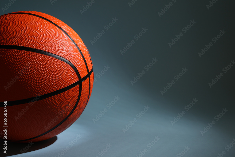 One orange basketball ball on dark grey background, closeup. Space for text