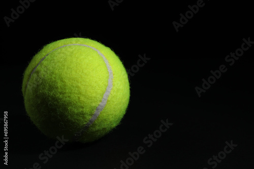 One tennis ball on black background, closeup. Space for text © New Africa