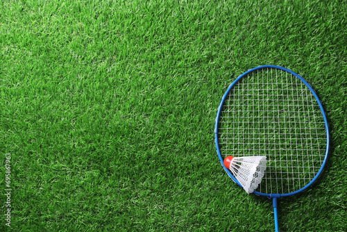 Two badminton racket and shuttlecock on green grass, top view with space for text