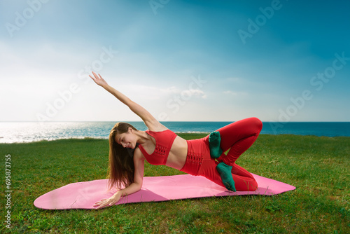 Athletic slim girl doing yoga stretching exercises during training near the sea, Yoga by the water: Young woman embraces solitary stretches, finding peace along the shore © Denys Kurbatov