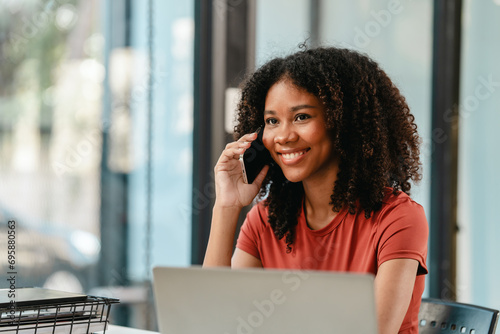 Portrait of joyful African American woman people with an afro hairstyle, working on a laptop at a desk with documents.
