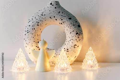 Fairy little angel candel with wings on white background. Shiny lights, miracle, Christmas mood concept. Copy space. Scandinavian design decoration.