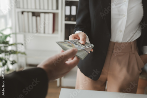 Foto Handing stacks of money to each other in the office, Give money to officials for some business-related reason, Receive kickbacks from corruption in business