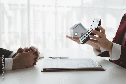 A real estate agent sits in her office, The salesperson is presenting what the home the customer is about to buy looks like, The broker is calculating the buyer's monthly instalment payments. photo