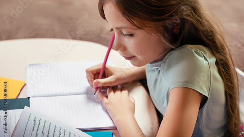 Uma menina de cabelos compridos, escrevendo em um caderno. Conceito de volta às aulas. photo