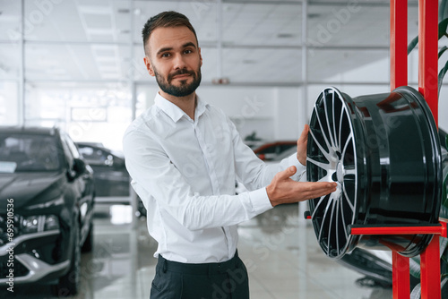 Worker in formal clothes is in the auto salon photo
