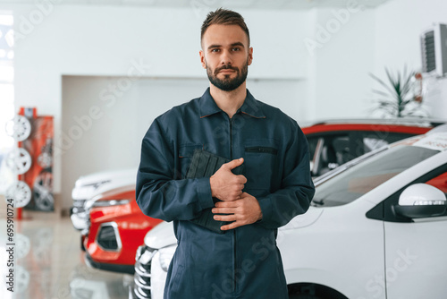 Standing and holding tablet in hands. Car repairman is in the garage with automobile © standret