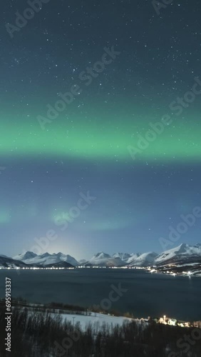 Green Northern Lights on Night Sky with Stars and Snowy Mountains at Winter Night. Balsfjorden, Troms, Norway. Time Lapse. Vertical Video photo