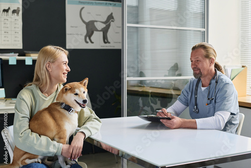 Veterinarian and dog owner having positive conversation during checkout in clinic