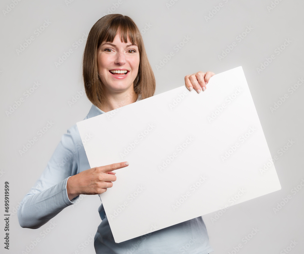 Young woman with is pointing to an empty advertising board in her hand Young woman with is pointing to an empty advertising board in her hand
