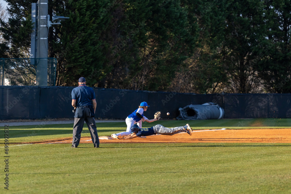 Obraz premium High School Baseball Player Sliding Head First into Third Base