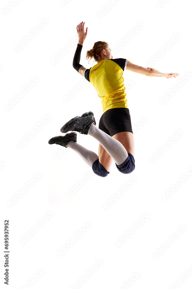 Full-length image of young athletic woman, volleyball player in motion, playing and hitting ball isolated over white background. Concept of sport, competition, active and healthy lifestyle, hobby