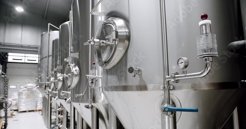 Stainless steel tanks at brewery factory. Vat container with beer brewing. Process of fermentation and maturation. Modern equipment on plant