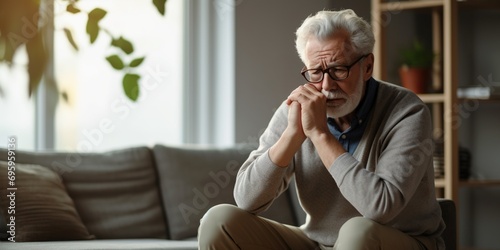 Elderly man experiencing symptoms of pancreatitis, gastritis, or colitis, seated alone in the living room, concept of Loneliness photo