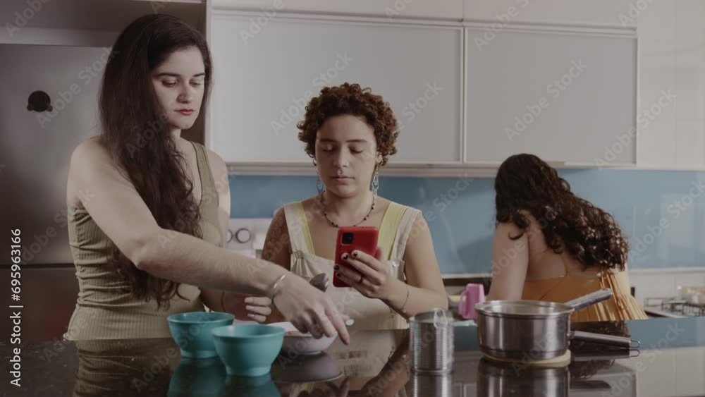 Mulheres na cozinha usando um smartphone para conferir uma receita. Cinematografico 4k.