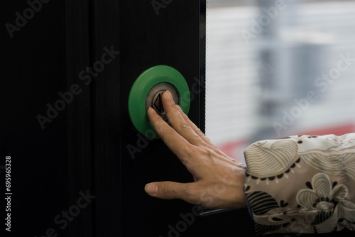 Female hand presses the door control green button to open doors in transport. photo