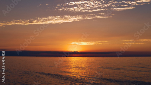 Beautiful sunset on the seaside, the sun has set behind the clouds, calm Baltic Sea in Vecāķi