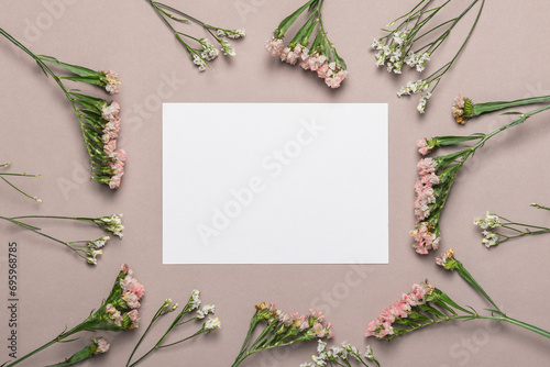 Empty card on a brown background with flowers and copy space. Greeting card, mockup.