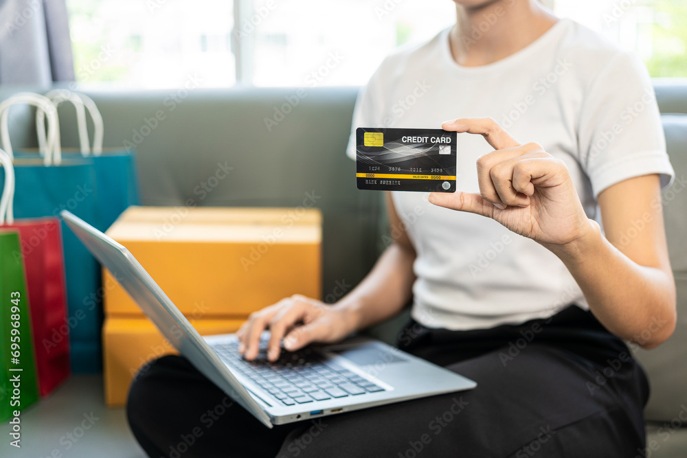 Online internet banking smiling young Asian woman's hand holding a credit card to transfer or pay without cash at home Financial technology, online name concept Online internet banking smiling young Asian woman's hand holding a credit card to transfer or pay without cash at home Financial technology, online name concept