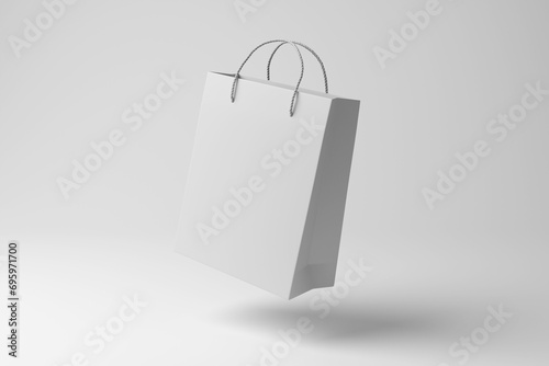White shopping bag floating in mid air on white background in monochrome and minimalism. Illustration of the concept of seasonal consumerism