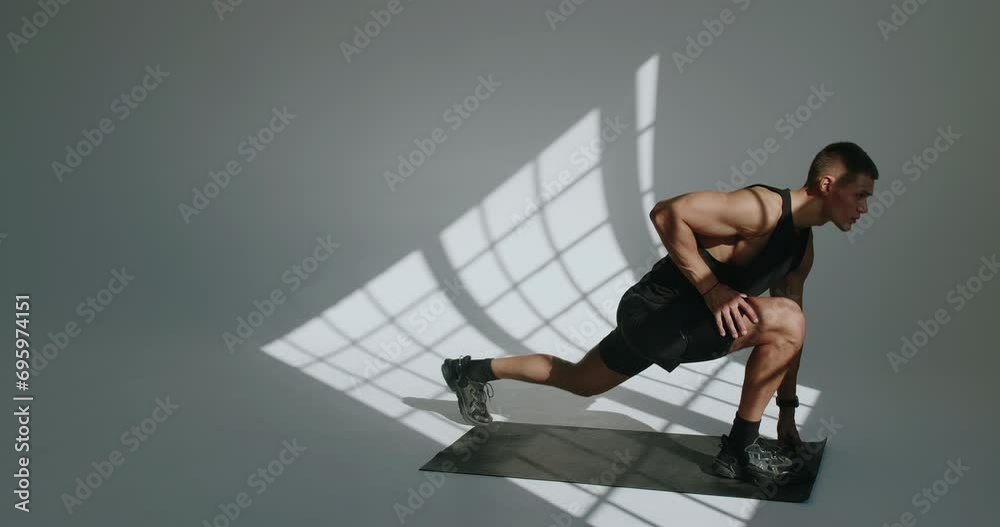 Young athletic man preparing body to workout and doing warm up exercises. Muscular male doing stretching on yoga mat in studio with white background Young athletic man preparing body to workout and doing warm up exercises. Muscular male doing stretching on yoga mat in studio with white background