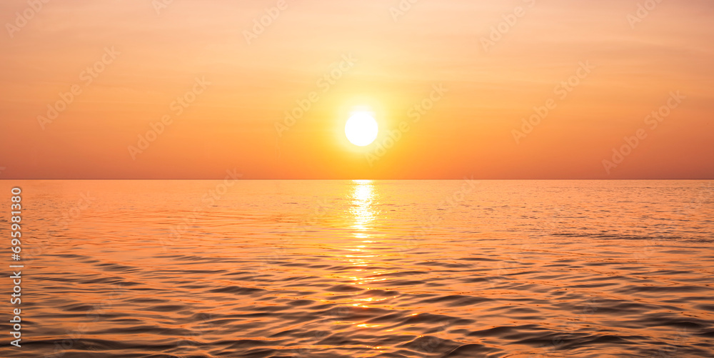 Beautiful orange sunrise sky background over sea with yellow sunlight reflection on sea surface in golden hour time, panoramic view