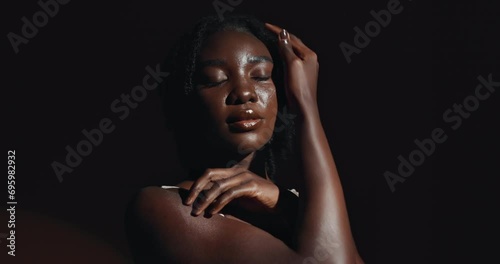 Face, hands and skincare with a natural black woman on a dark background in studio for feminine wellness. Arms, beauty and spa with a confident young model touching her body or skin in satisfaction photo