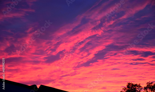 Incredibile tramonto con nuvole colorate di magenta sopra i tetti delle case  photo