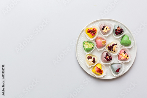 Plate with different chocolate on colored background. Assortment of fine chocolates top view vith copy space Health and obesity concept