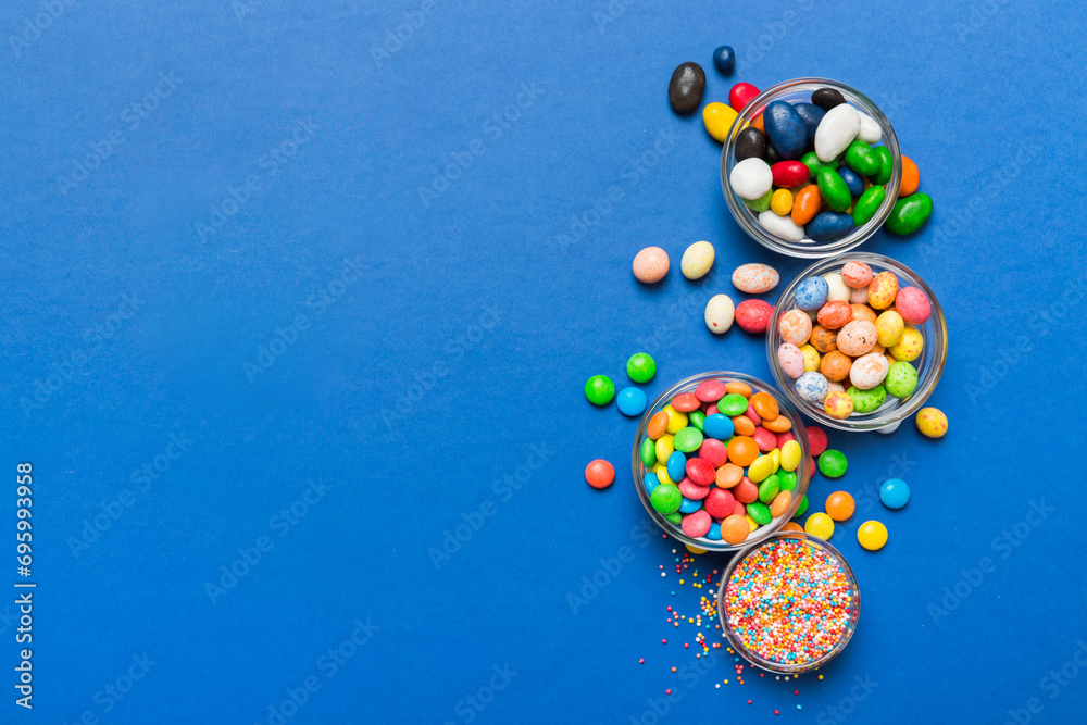 different colored round candy in bowl and jars. Top view of large variety sweets and candies with copy space