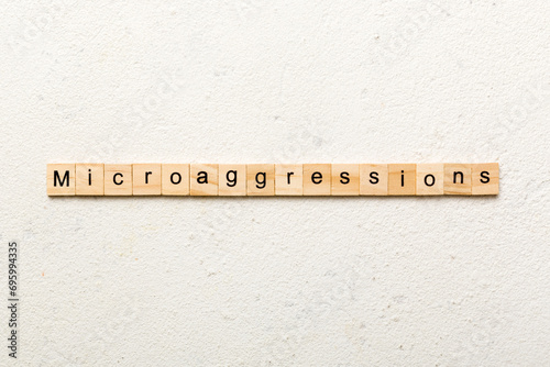 Microaggressions word written on wood block. Microaggressions text on cement table for your desing, concept photo