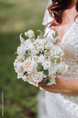 The bride is holding a wedding bouquet. Cropped photo. Details at the wedding. White lace dress