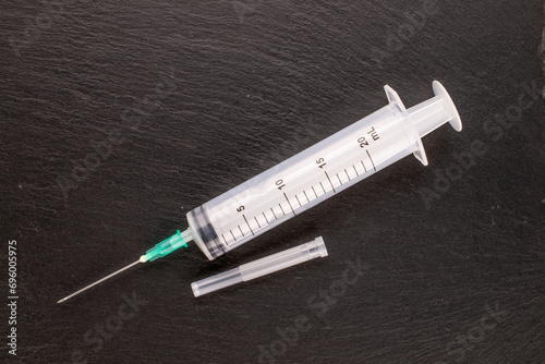 One plastic medical syringe with needle on slate stone, macro, top view.