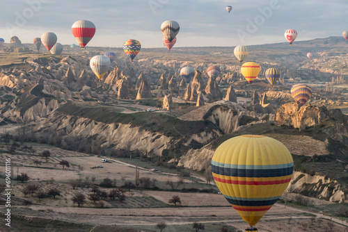 numerous hot air balloons flying over sun-lit fairy chimneys in Cappadocia, Göreme, Turkey photo