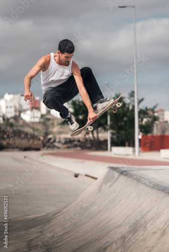 young man skater jumps from the ramp of a skate park. vertical composition photo